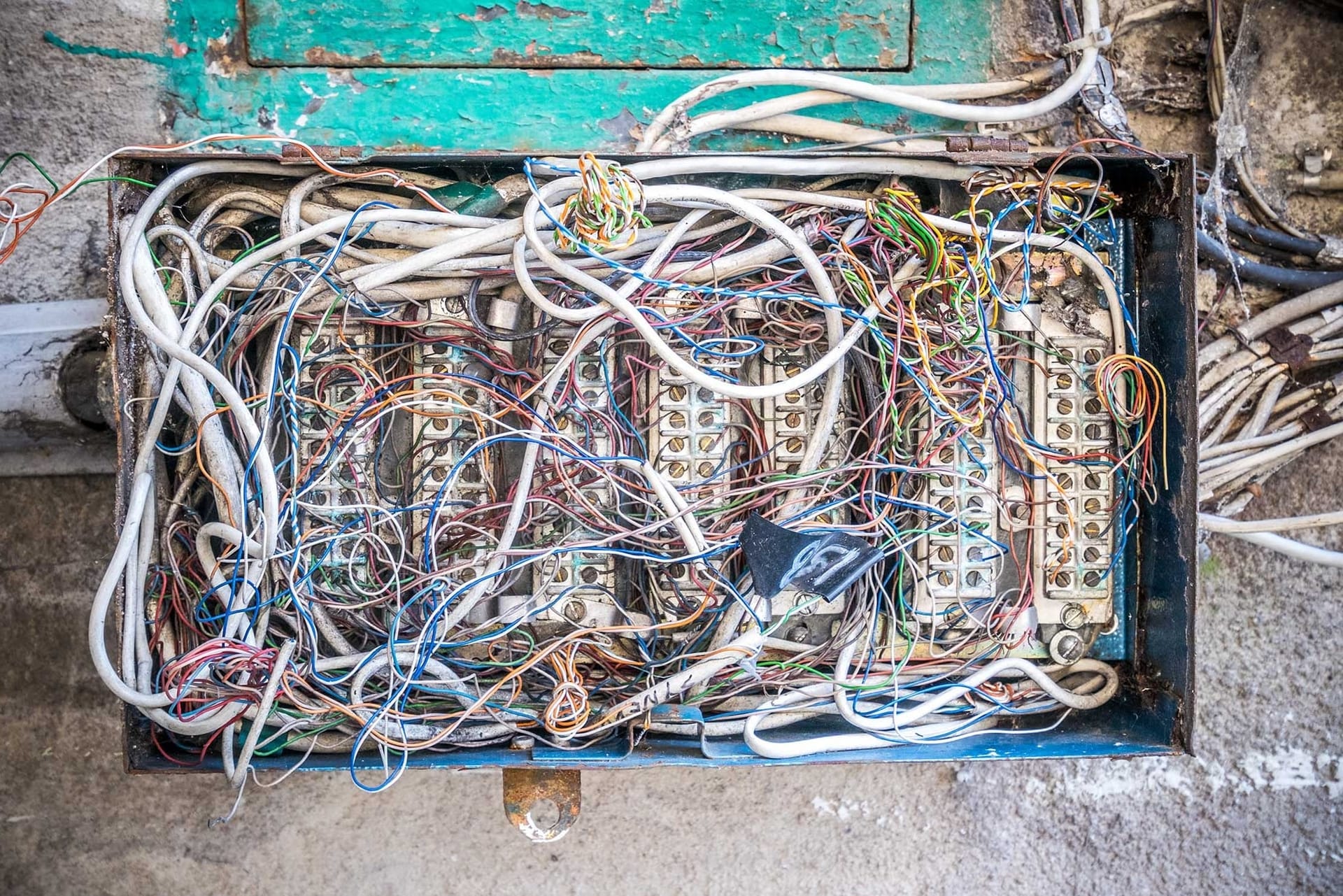 A tangled, unlabeled mass of wires inside an electrical breaker panel